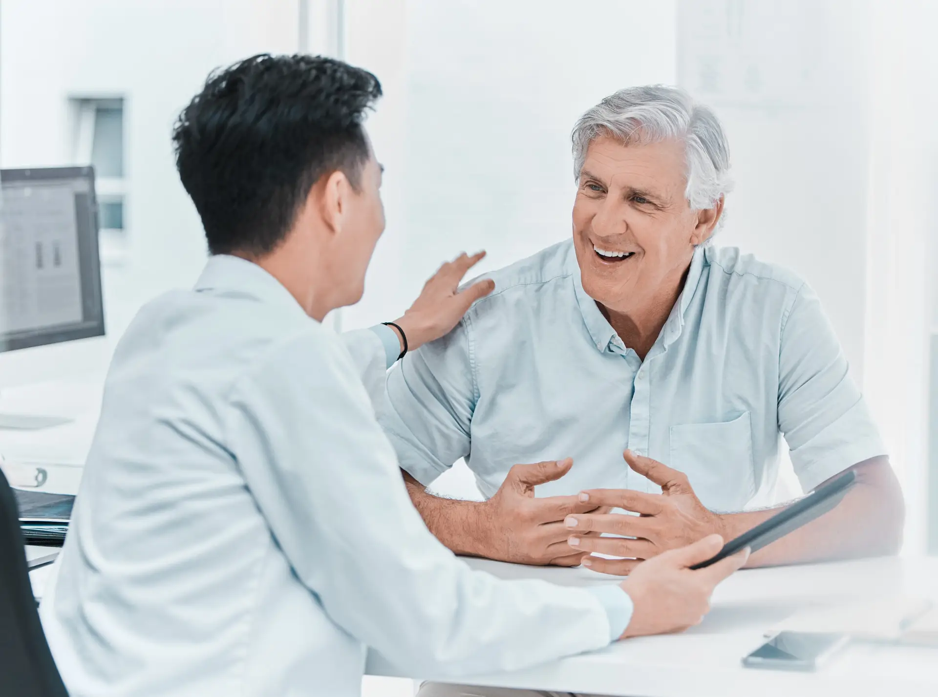 Mature male patient and doctor reviewing medical results on a tablet in clinic