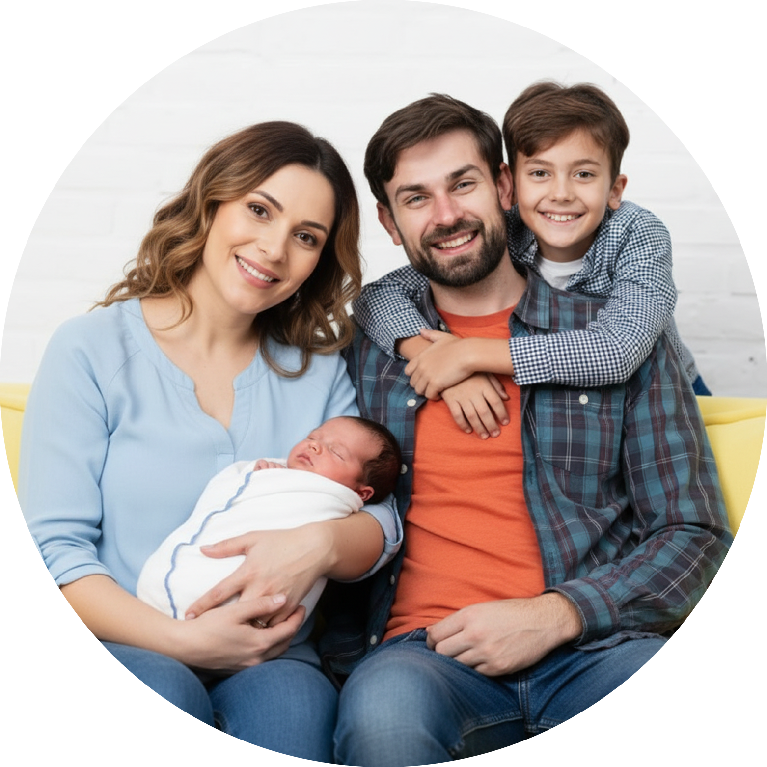 A smiling family of four sits together on a sofa. The mother holds a swaddled newborn, the father—radiating Men's Health—sits beside her, and an older son hugs his father from behind, all looking at the camera.