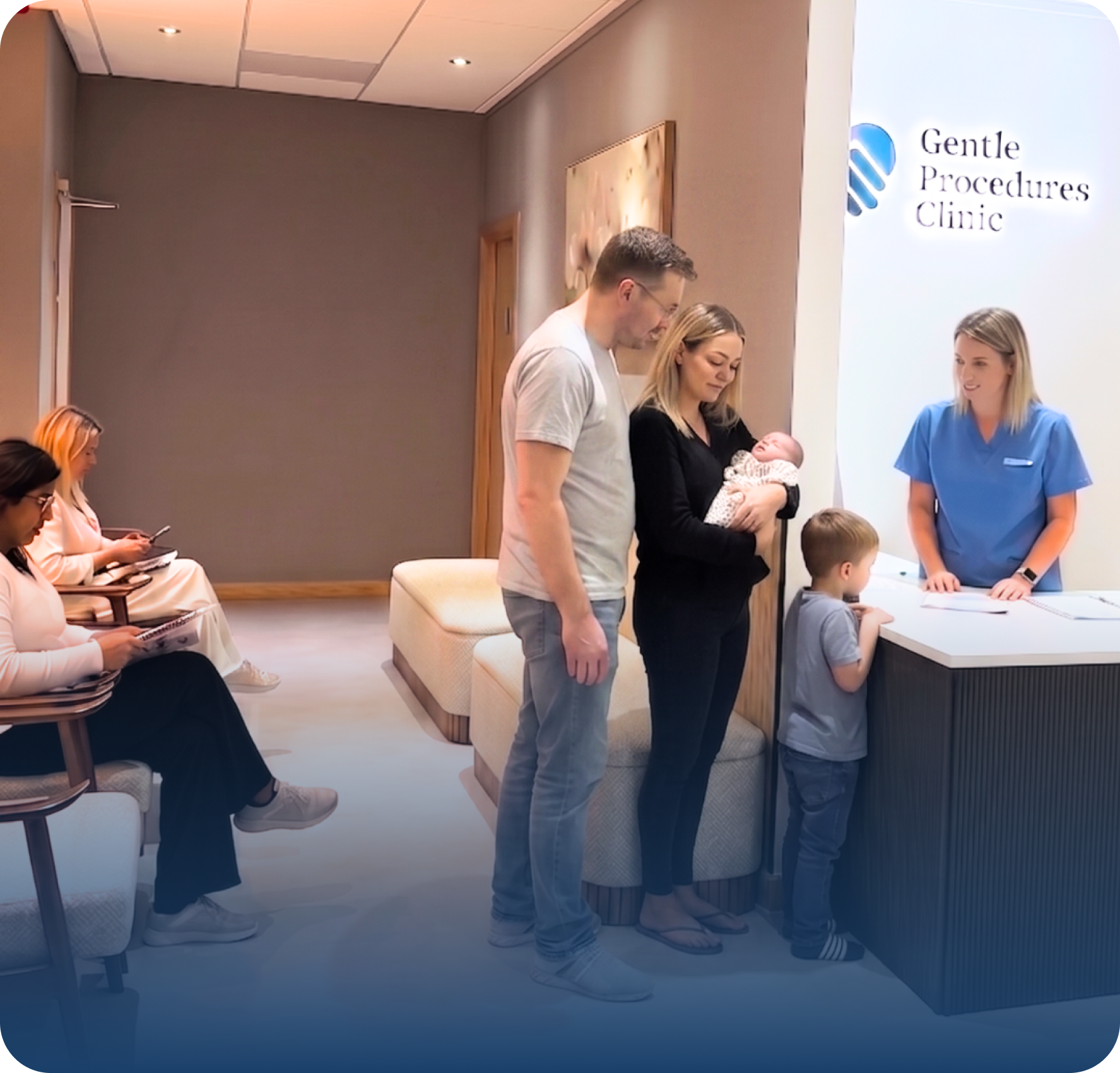 A family with a baby and young child stands at the Gentle Procedures Clinic reception desk, speaking with a staff member in blue scrubs. Two women are seated in the waiting area, looking at their mobiles; the clinic also specialises in Men’s Health.