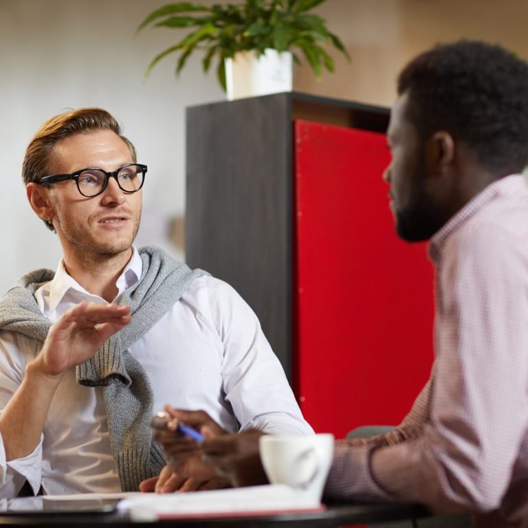 Modern young business specialists sitting in open-space office and discussing marketing project